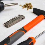 Drill bits, screws and a hammer on a white surface