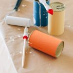 Paint cans and a roller on a protective sheet